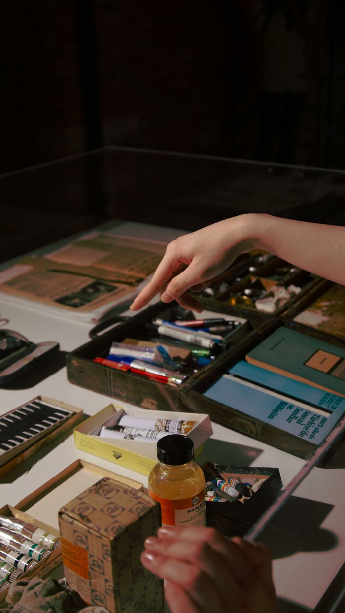 A close-up of art supplies displayed on a table at an indoor exhibition, highlighting creative tools.