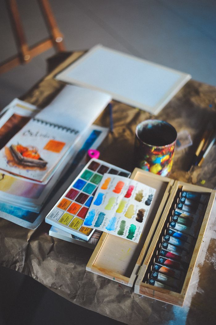 A collection of watercolor paints and art supplies on a textured surface, inspiring creativity.
