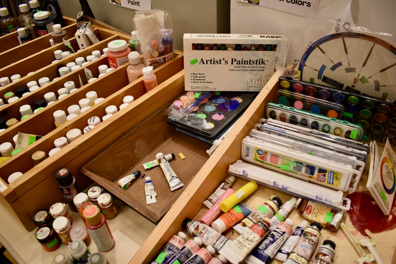 A variety of art supplies at a creative reuse center in Norfolk, Virginia, showcasing paints and other materials.