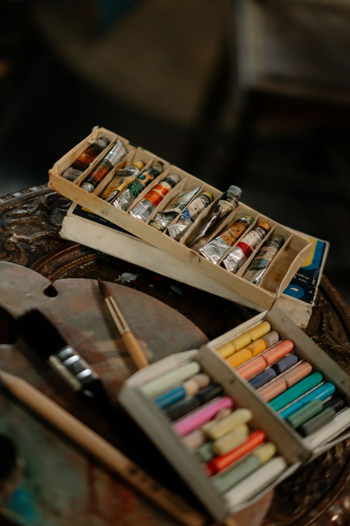 A variety of art supplies including pastel sticks and oil paints in an artistic setting.